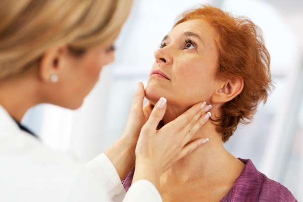 a doctor checking a woman's neck for hypothyroidism symptoms