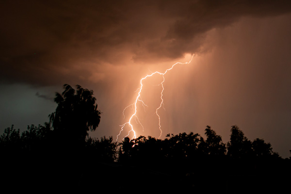 a large lightning bolt striking from a dark sky during a severe thunderstorm