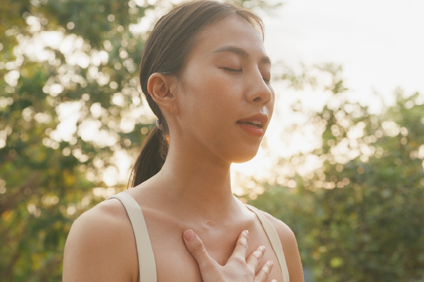 a woman with her hand on her chest taking a deep breath