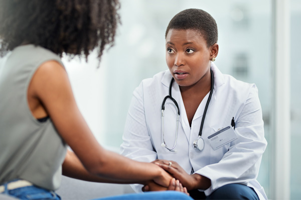 a Black woman doctor comforting a woman waiting for her breast cancer diagnosis