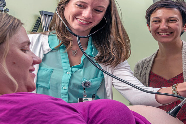 obgyn patient and midwife with a stethoscope listening to her stomach