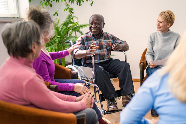 a group of diverse older people chatting with a counselor at a COPD support group session