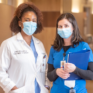 nursing colleagues standing side by side in a hospital hallway wearing masks