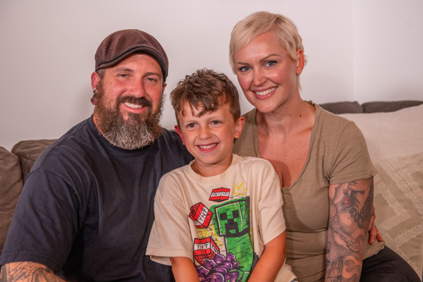 Jenn Venn smiling for a photo with her husband, Seamus, and her son, Merek