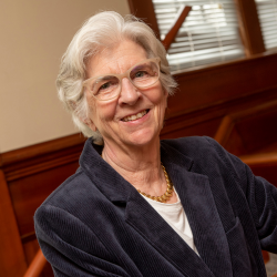 Denise Mullen looking at camera and smiling while standing in front of staircase