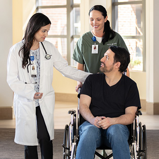 hospital transport staff wheeling patient in wheelchair down hallway
