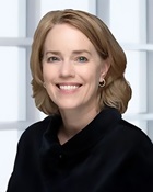 a woman with shoulder-length blonde hair wearing a dark shirt and smiling for the camera