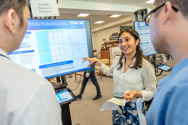 researchers engaging with a touch screen presenting a research poster