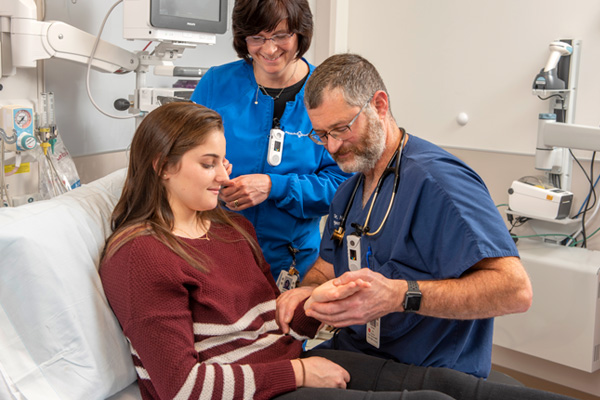 doctor checking patient’s hand with a nurse observing in the emergency room