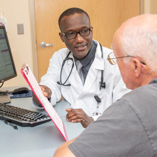 doctor mario lysse, holding a clipboard, consults with a patient