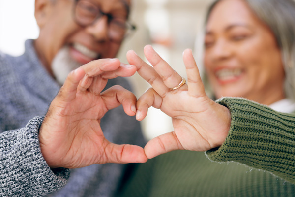 an older couple making a heart with their hands to celebrate Heart Month